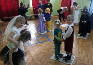 Na zdjęciu znajdują się dzieci w strojach karnawałowych biorące udział w zabawie taniec na gazecie